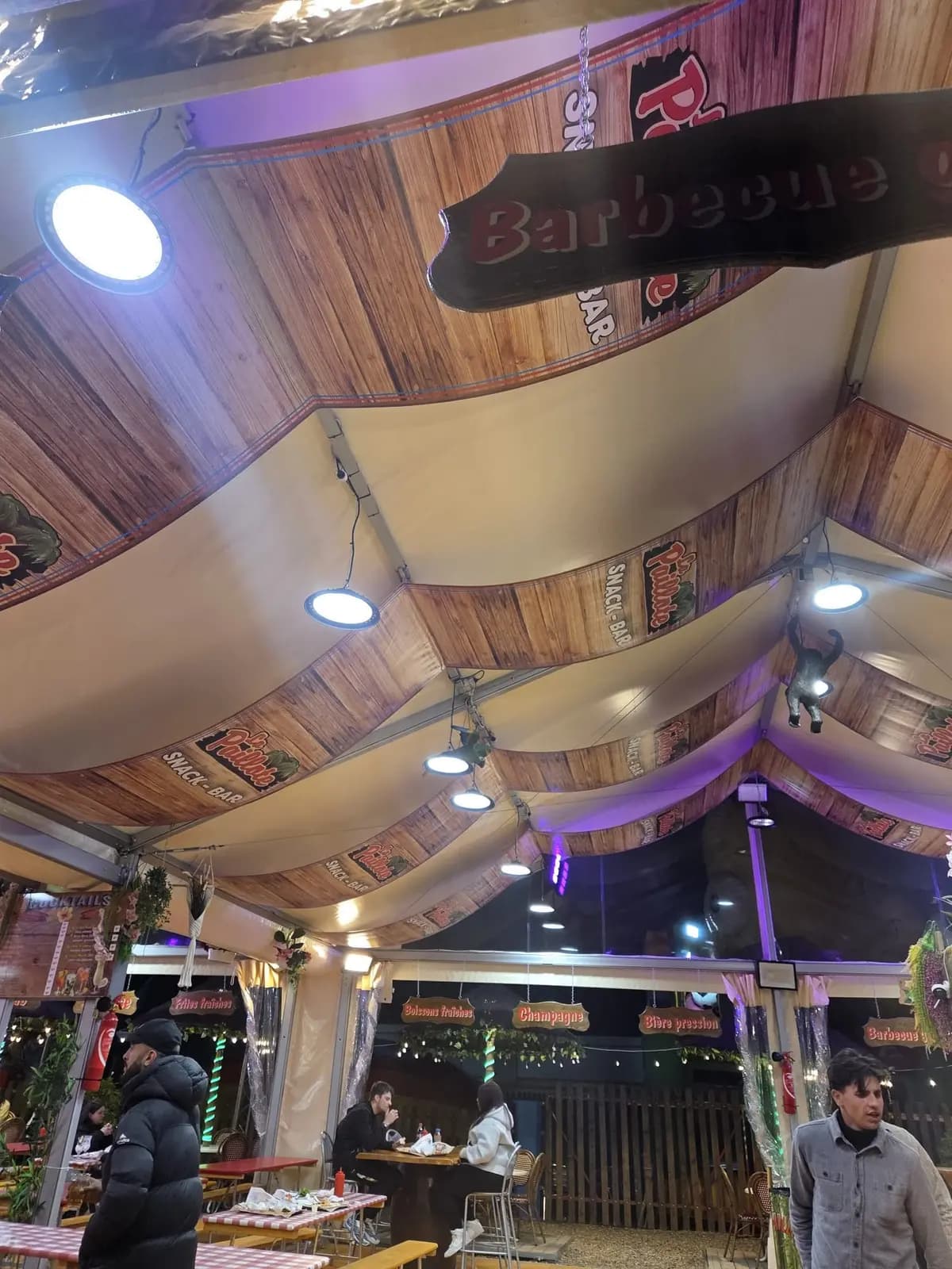 Vue du plafond en toiles imprimées bois d'un snack bar avec enseignes lumineuses
