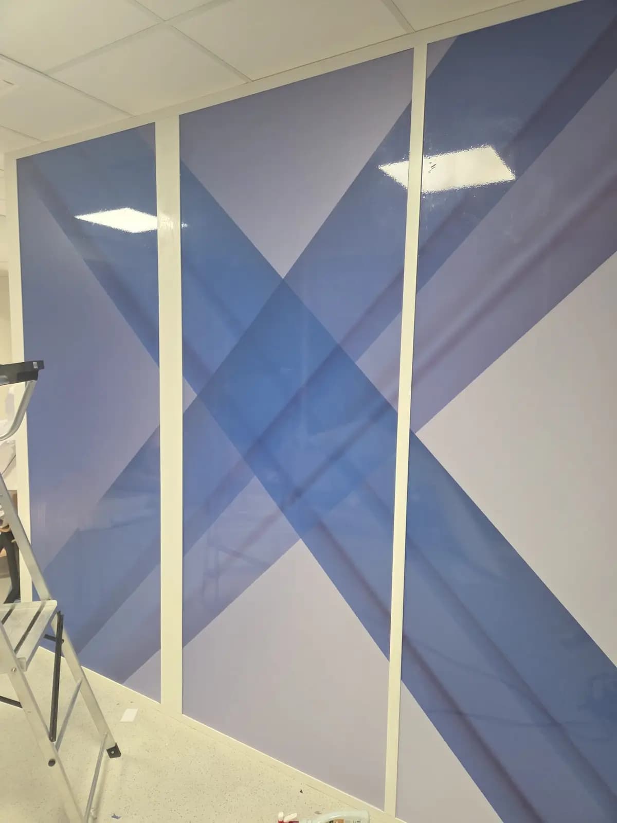 Adhésif mural grand format à croisillons bleus en cours de pose