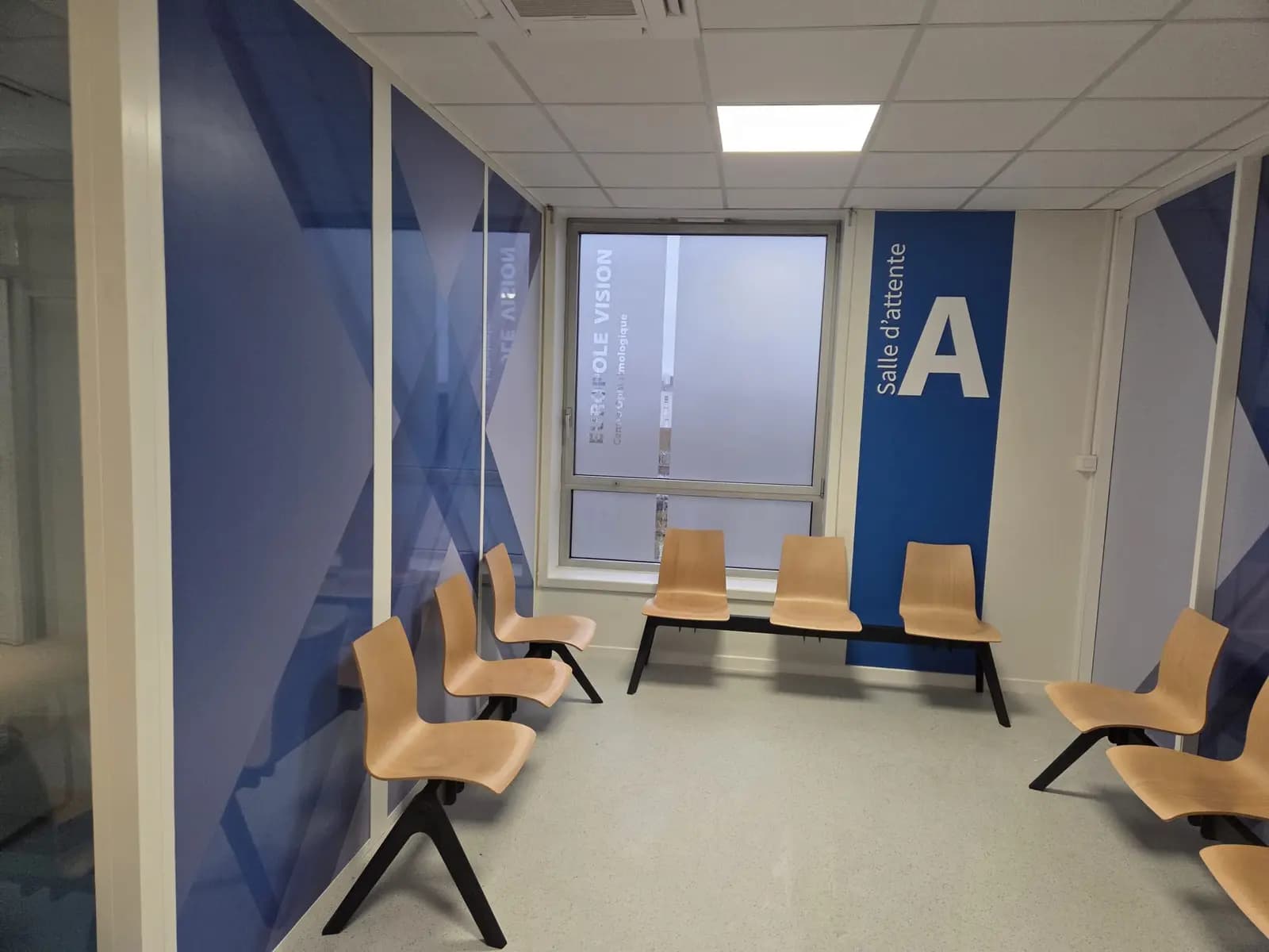 Salle d'attente avec murs décorés d'adhésifs géométriques bleus et signalétique Salle A