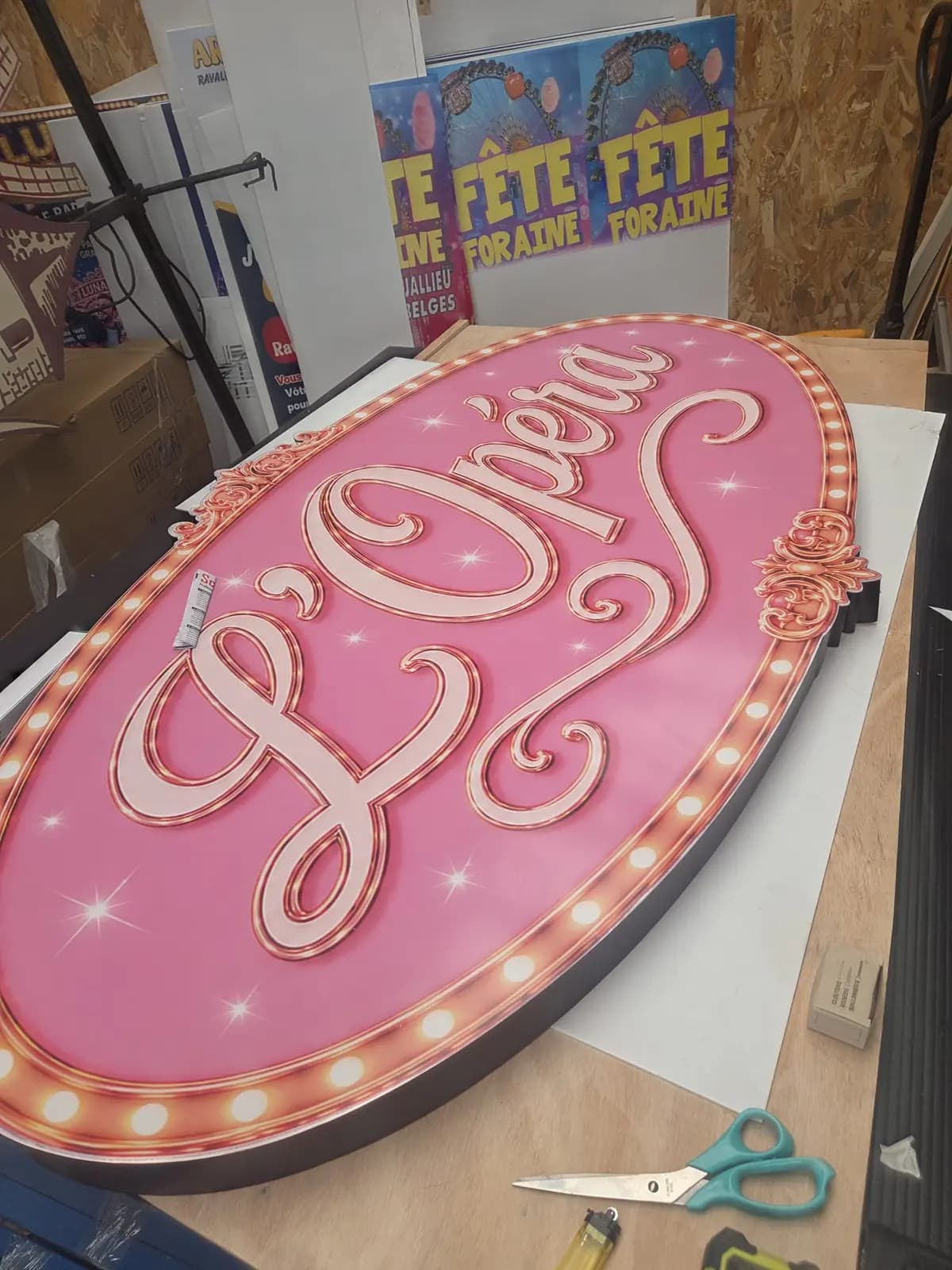 Caisson d'enseigne L'Opéra rose avec moulures et rampes d'ampoules sur table de montage