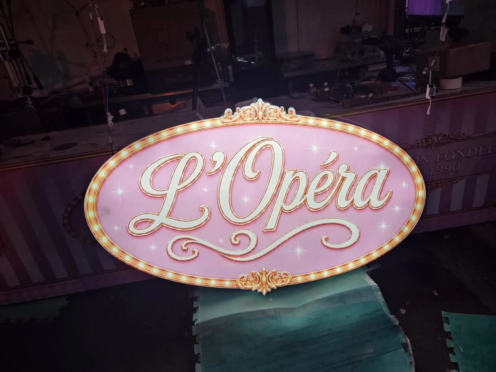 Enseigne lumineuse rose L'Opéra avec ampoules cabochons allumées en atelier