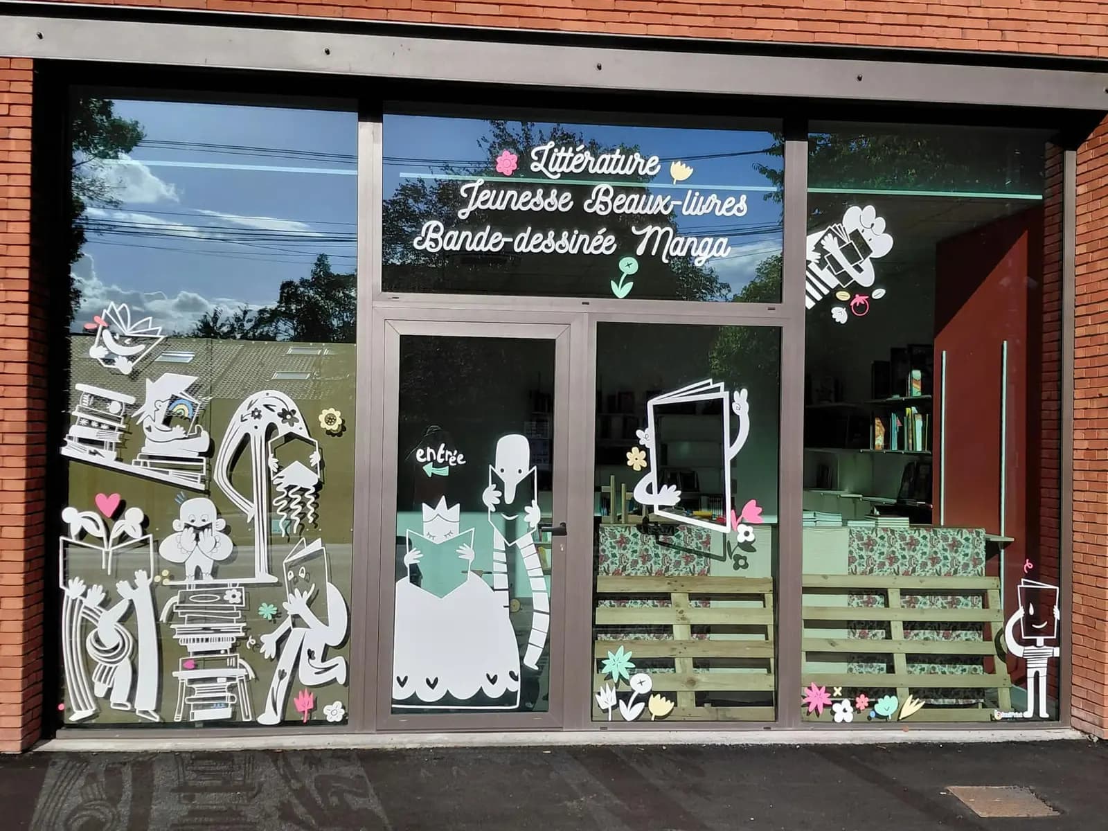 Adhésifs décoratifs blancs sur la vitrine d'une librairie jeunesse et bande dessinée